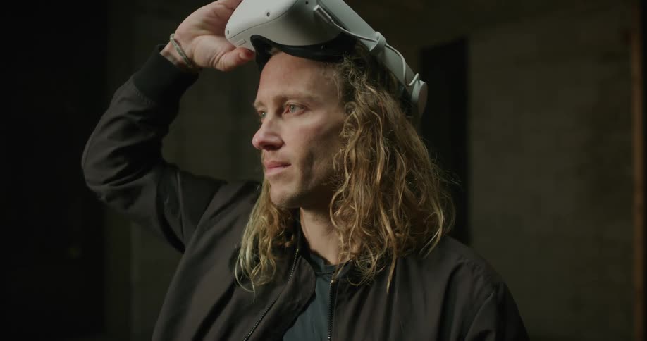 Man wearing jacket lifts vr headset from off his eyes