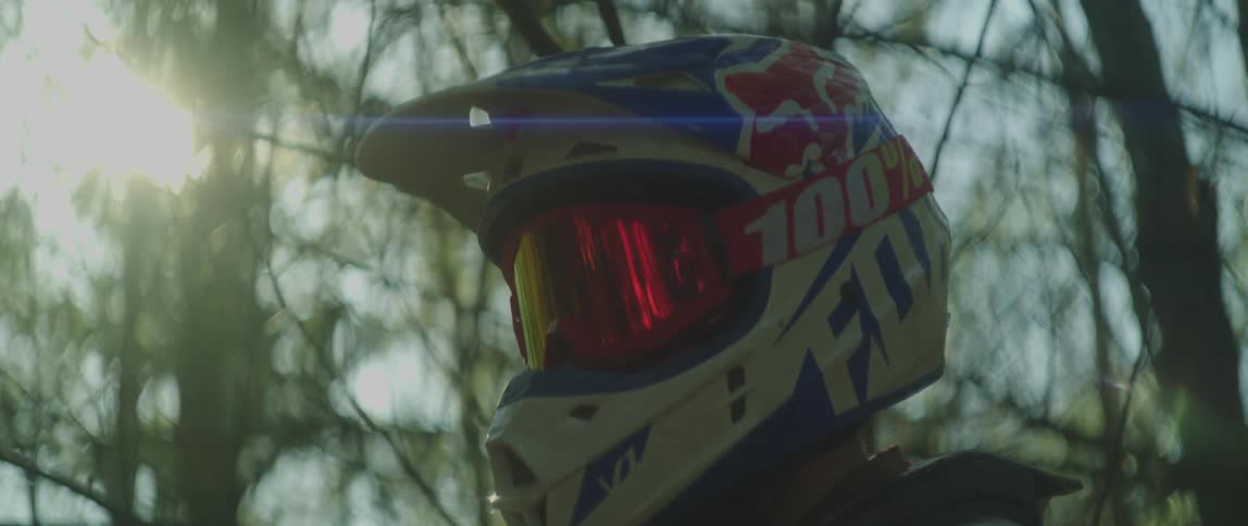 A man is wearing a motorcycle helmet outdoors at dusk