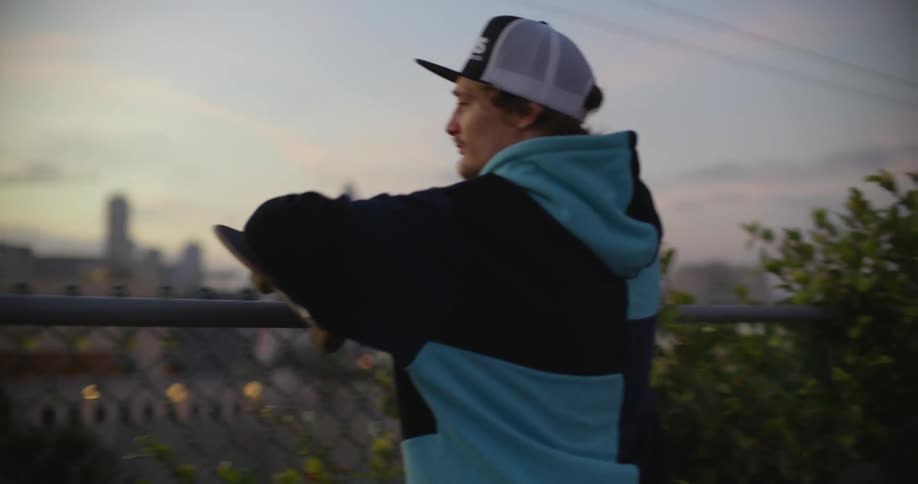 A man leans on the fence looking at the city