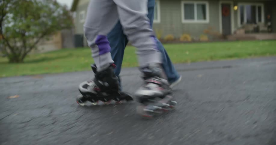 Mother helps daughter to learn how to roller skate on the street of the neighborhood