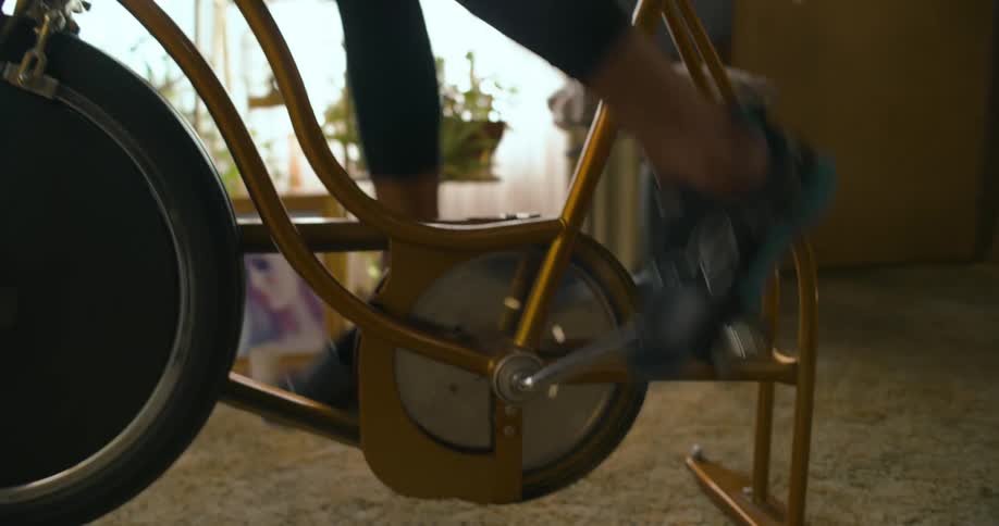 An elderly woman riding a vintage stationary bike in her living room
