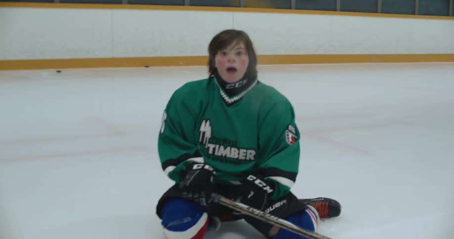 A hockey player hits the puck with the hockey stick and then falls on the ice