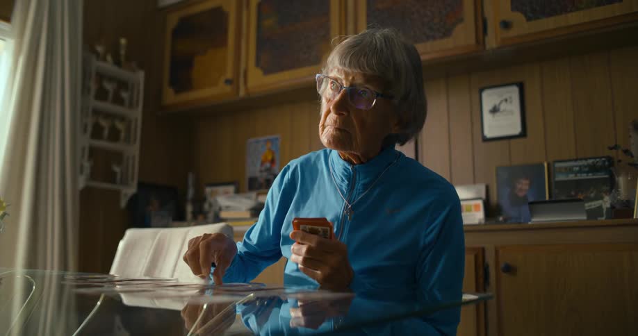 A woman lays playing cards down one by one on a glass dining room table