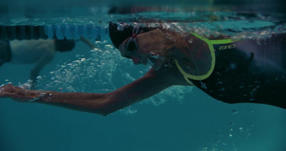 An elderly woman swims beneath the surface of a lane in a swimming pool