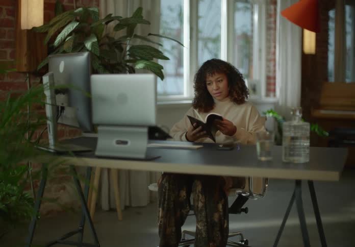 Woman leaves through book while video conferencing then smiles