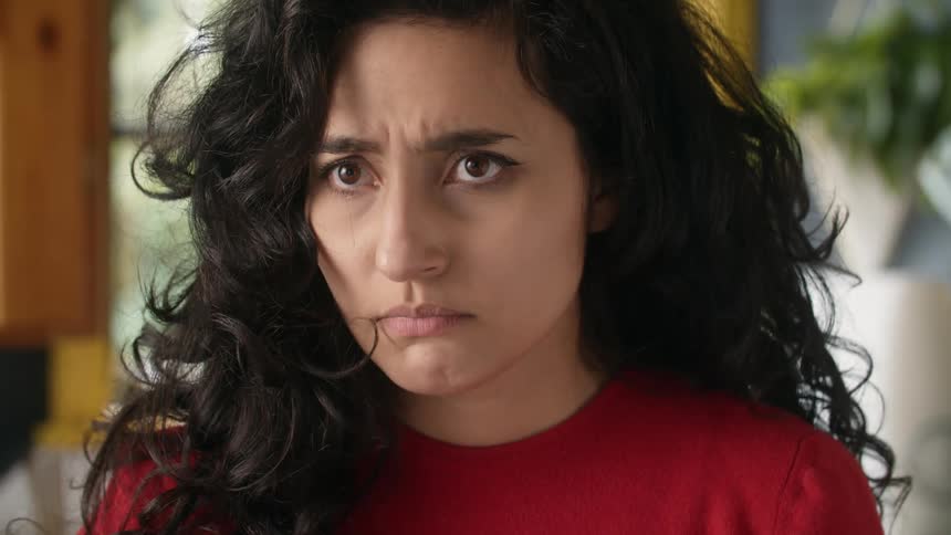 A woman looks unhappy as she has her hand on her stomach