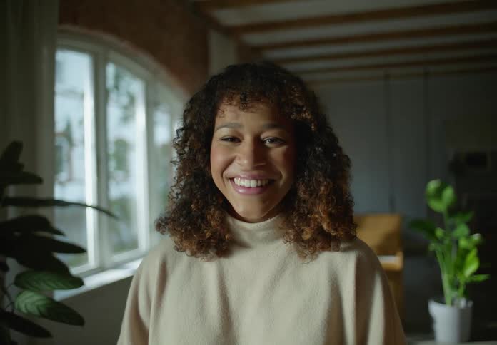 A woman is posing for the camera indoors and is smiling