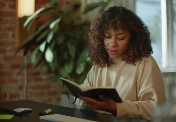 A woman is sitting at a table and reading a book