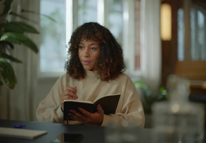 A woman is sitting at a table and writing in a journal