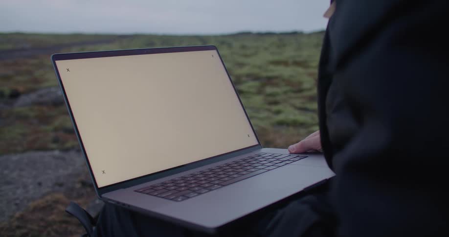 Someone is outside looking at a laptop computer