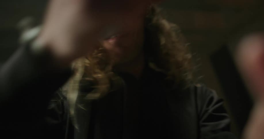 A man with long blond hair is wearing a virtual reality headset and playing a game