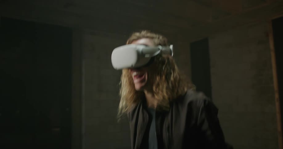 Blonde long haired man playing a virtual reality game in a vacant room