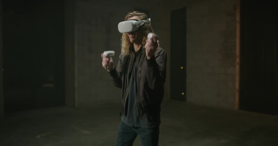 Young blonde long haired man plays with 3d virtual reality goggles over his eyes