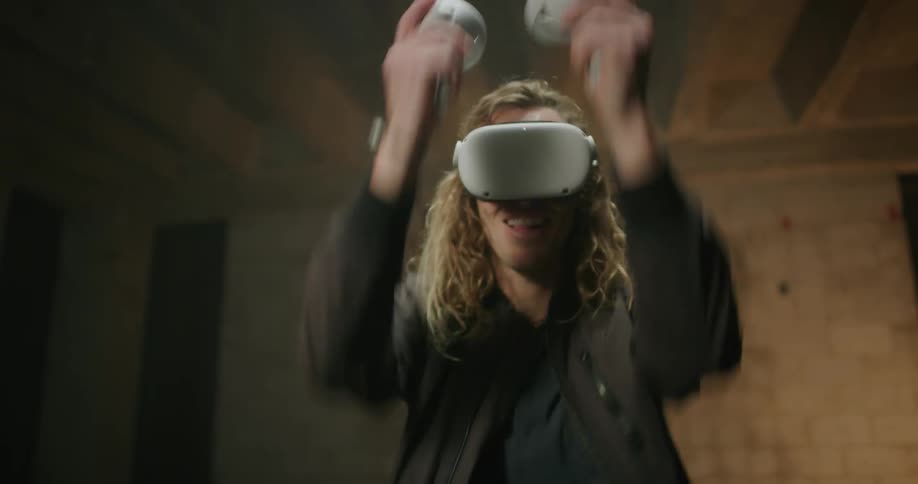 A man swings his controllers while playing a virtual reality game