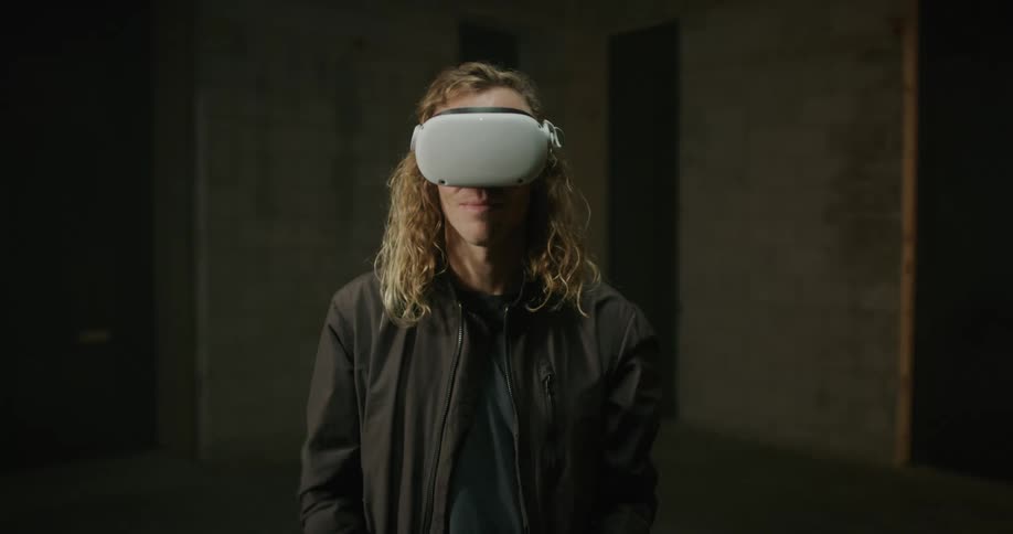 Young blonde long haired man puts on 3d virtual reality goggles over his eyes