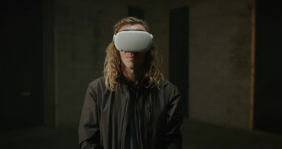 A man puts on a virtual reality headset while sitting in an empty room