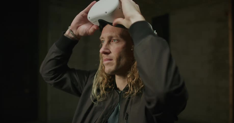Blonde man wearing jacket pushes up vr goggles