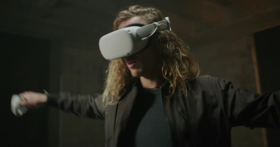 A man laughs and moves his arms back and forth while playing a virtual reality game