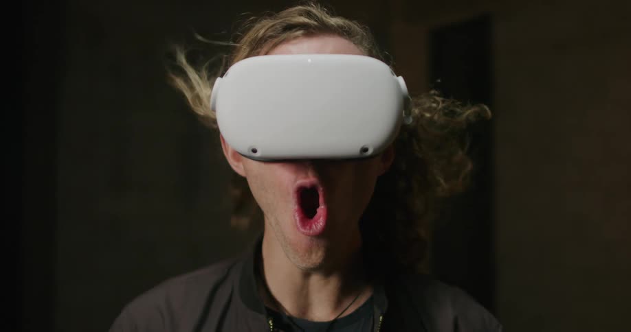 Man wearing 3d virtual reality goggles screams while his hair is blowed by the wind