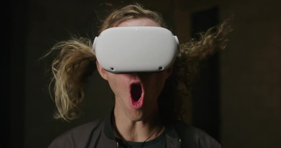 A teenage boy yells in amazement as he looks through virtual reality goggles