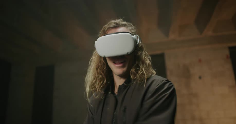 A man swings his controllers while playing a virtual reality game