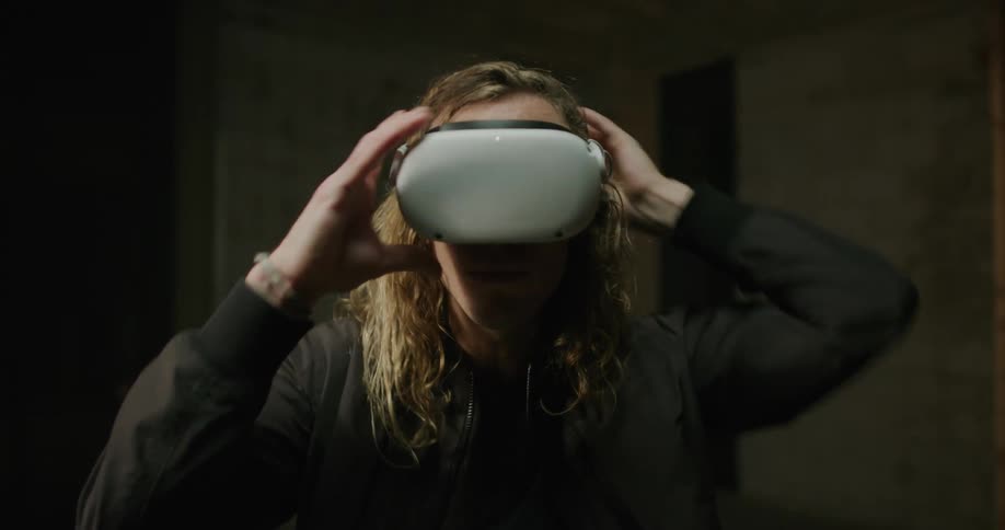 Blonde curly haired man putting on a head mounted device