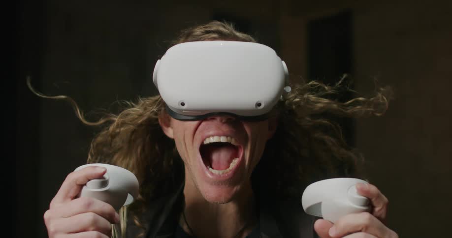 Man wearing 3d virtual reality goggles screams while his hair is blowed by the wind