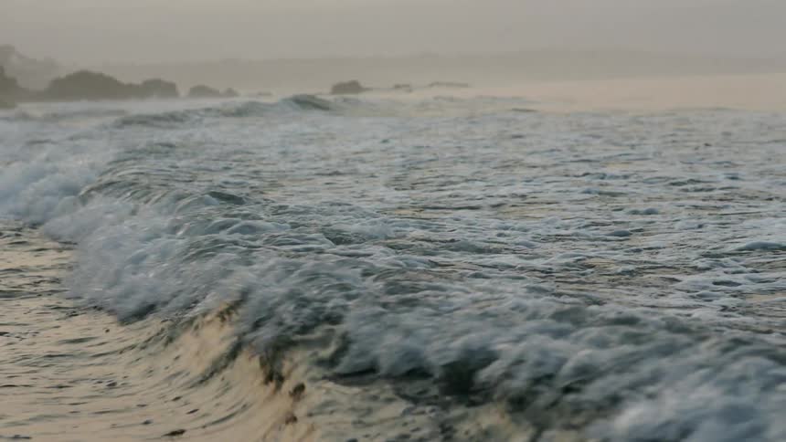 Waves crash on the shore on a foggy day
