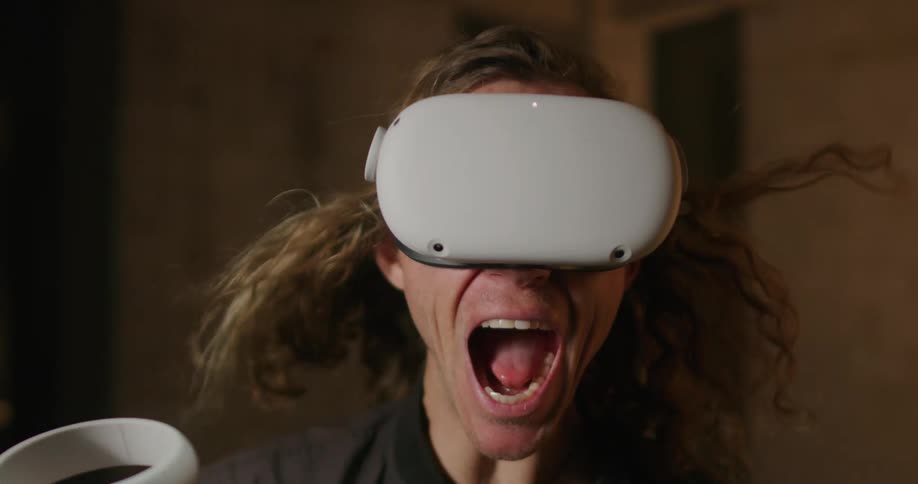 Man with long hair blowing screaming while wearing a virtual reality headset