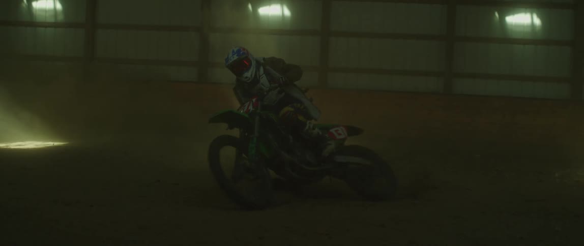 Man driving a motocross motorcycle on the interior of a dimly lit warehouse