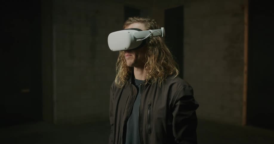 A man puts on a virtual reality headset while standing in an open room