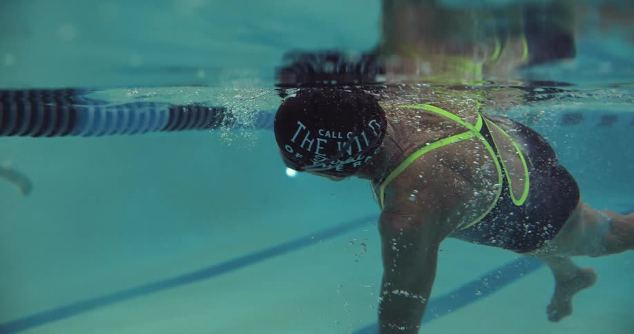 An elderly woman swims across a lane of a swimming pool