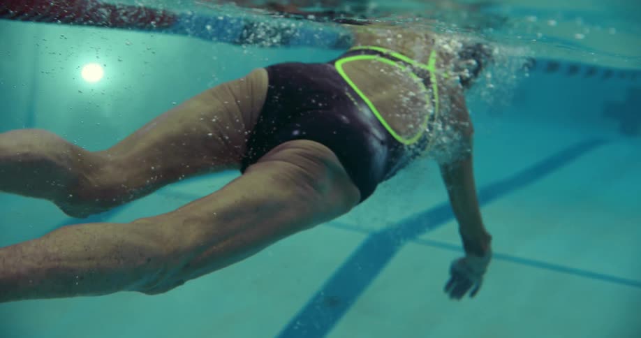 An elderly woman swims across a competition swimming pool