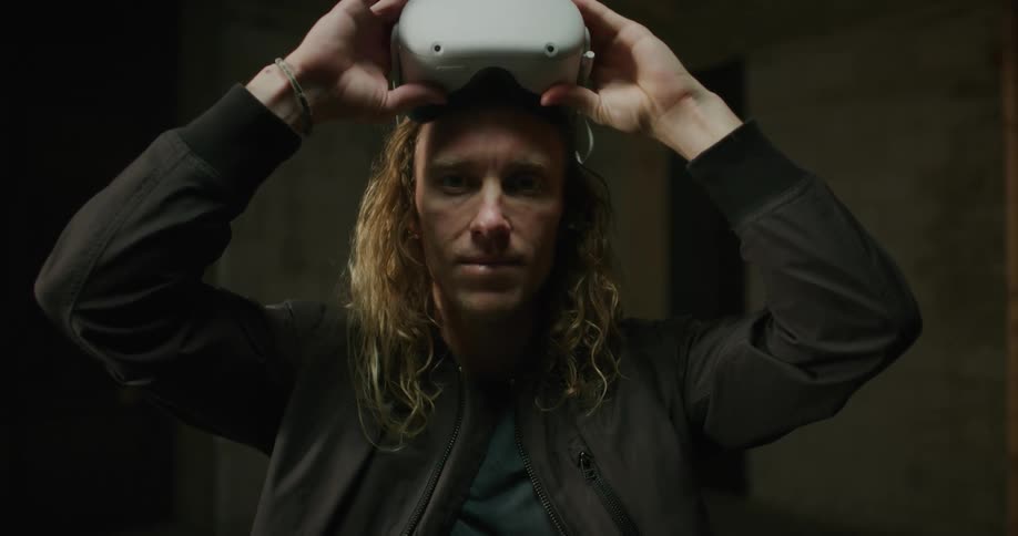 A man lifts the vr glasses hes wearing and stares straight ahead