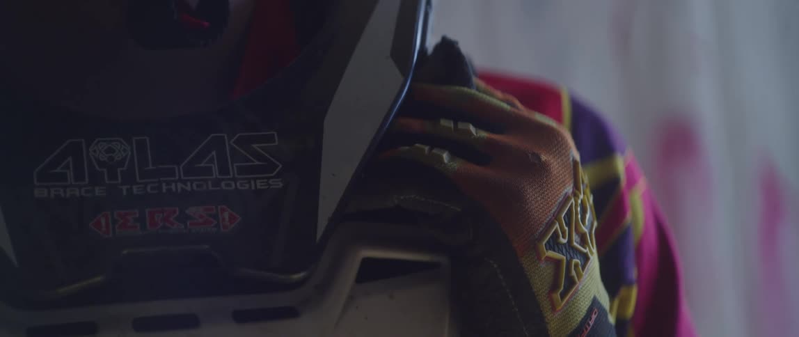 A person wearing a helmet and jersey is sitting indoors