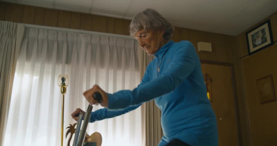 A woman rides an exercise bike in her home near the window