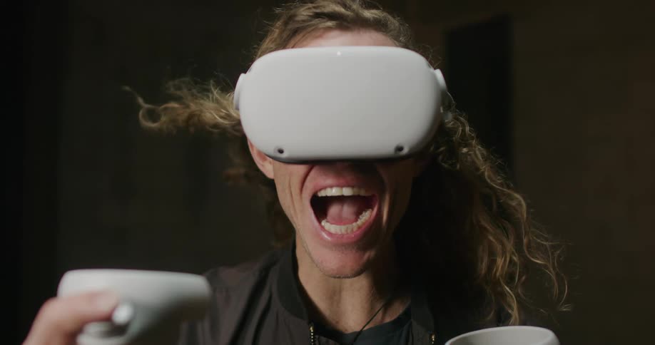 A man shouts while wind whips through his hair as he plays a virtual reality game