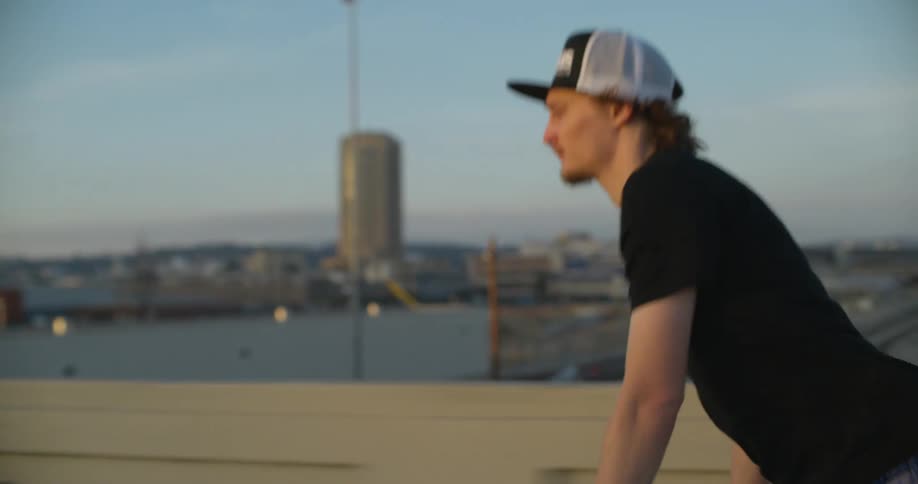 A man is skateboarding on a bridge in an urban city at dusk