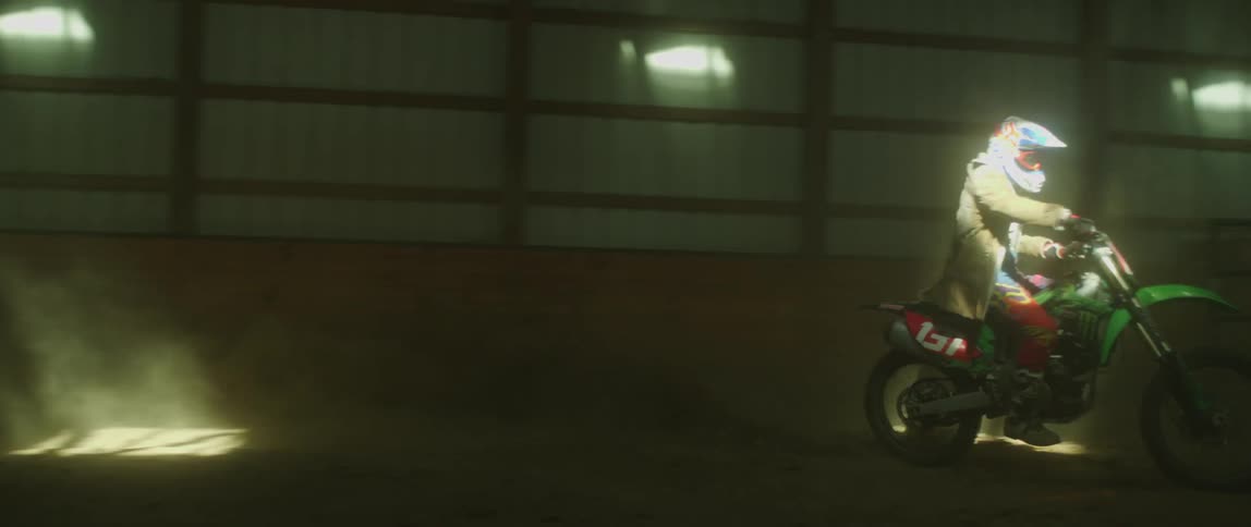 Person rides motorcycle in large dimly lit empty building