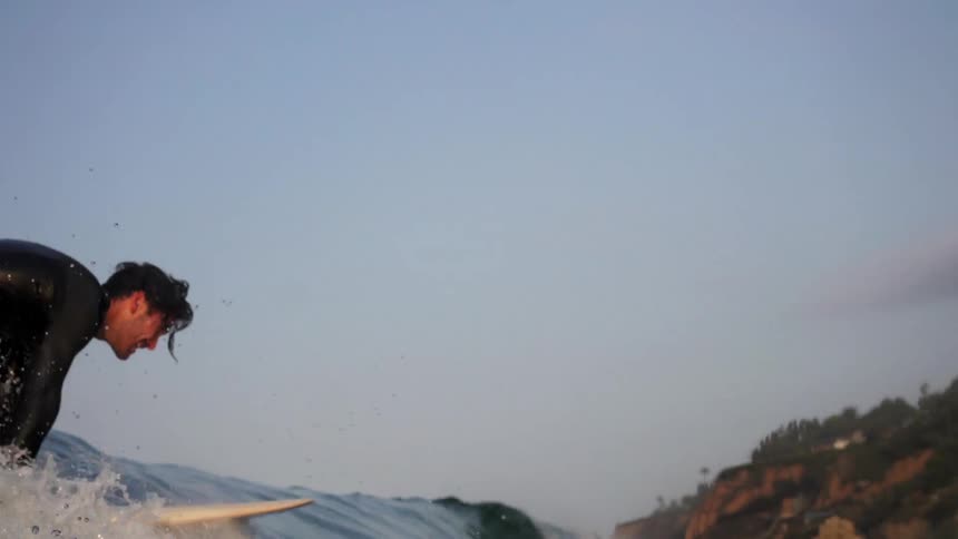 A man stands up on his surfboard