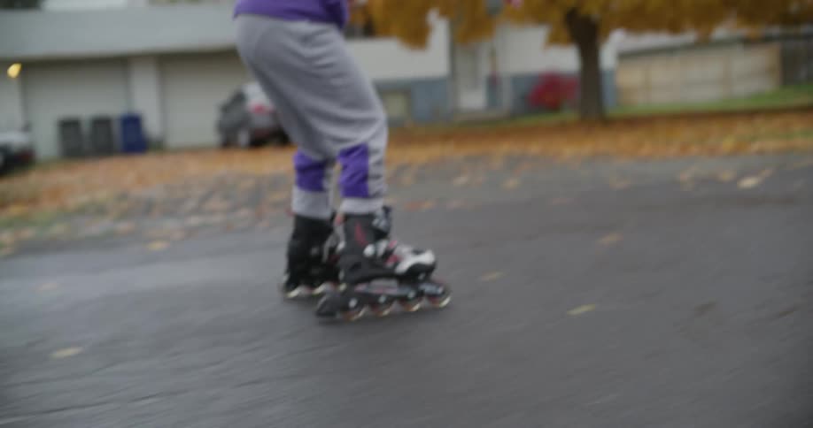 A woman is helping a girl learn to rollerskate in a neighborhood
