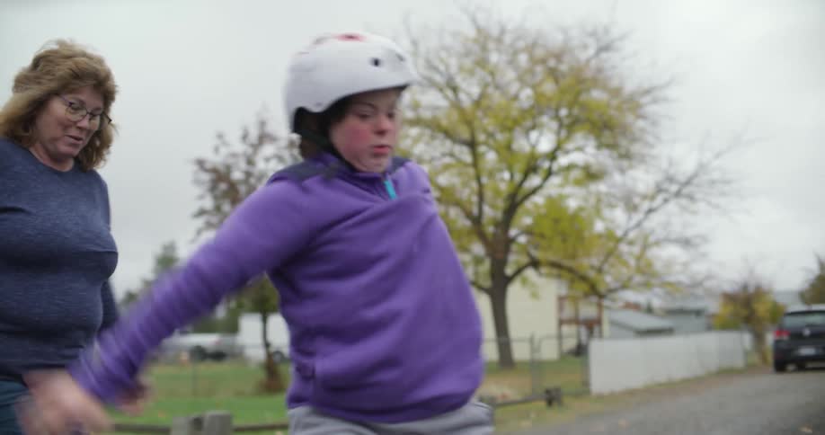 People help girl learning to skate using inline skates