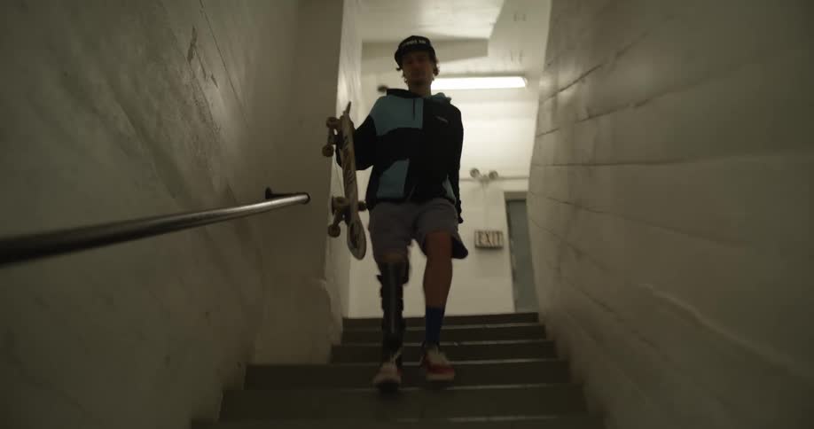 A kid runs down the stairs with a skateboard in hand