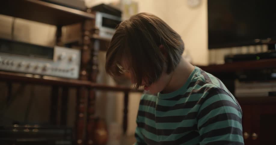 A girl sits on the floor at home in front of a game and unfolds a piece of paper