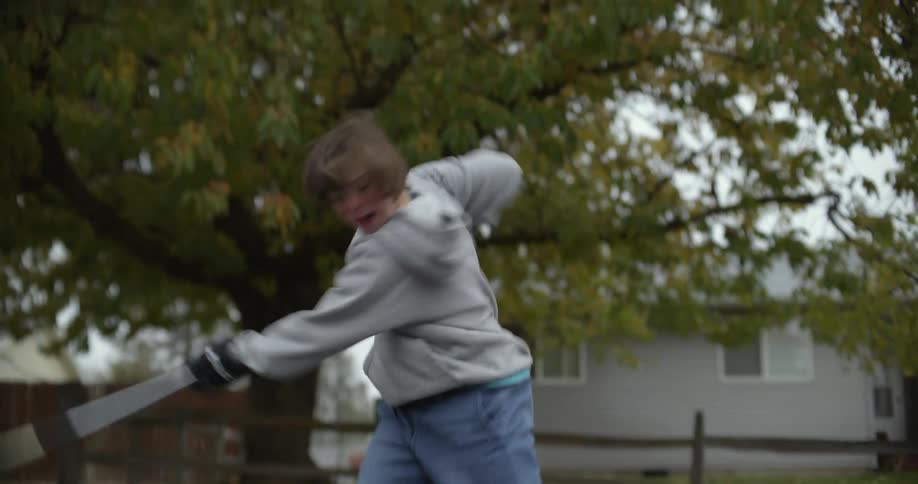 Young girl practicing hockey on the street of the neighborhood swings her stick and celebrates