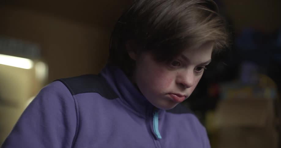 Teenager wearing lavender talks and looks down in garage