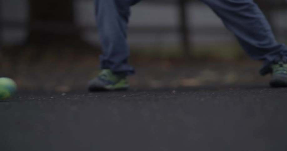 A child hits a ball back and forth with a stick as they play street hockey outside