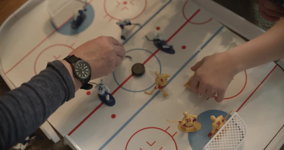 Two people are playing a board game with hockey figures