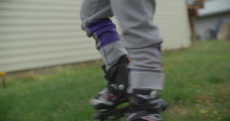 Inline skater walks carefully across lawn near house