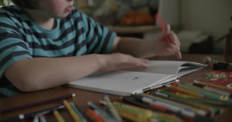 A young girl sits at a table at home and colors